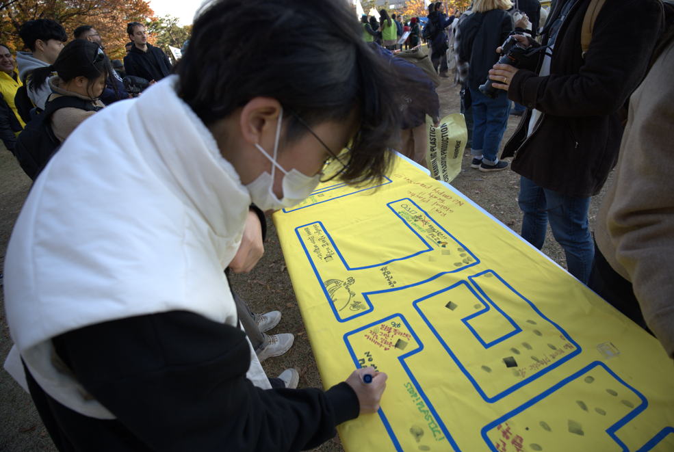 23일, 전 세계 시민 1,000여 명과 16개 환경단체로 구성된 ‘플뿌리연대’가 벡스코를 중심으로 ‘강력한 국제 플라스틱 협약을 위한 1123 시민행진’에 나선 가운데, 행진 도착점에서 시민들이 ‘플라스틱, 이제 그만(No More Plastic)’ 메시지 현수막에 손도장을 찍고 있다. 사진=플뿌리연대
